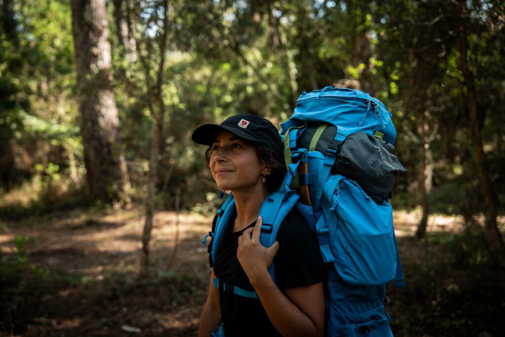 Trekkeuse équipée pour la Fjällräven Classic en Laponie avec un sac à dos chargé sur un sentier forestier